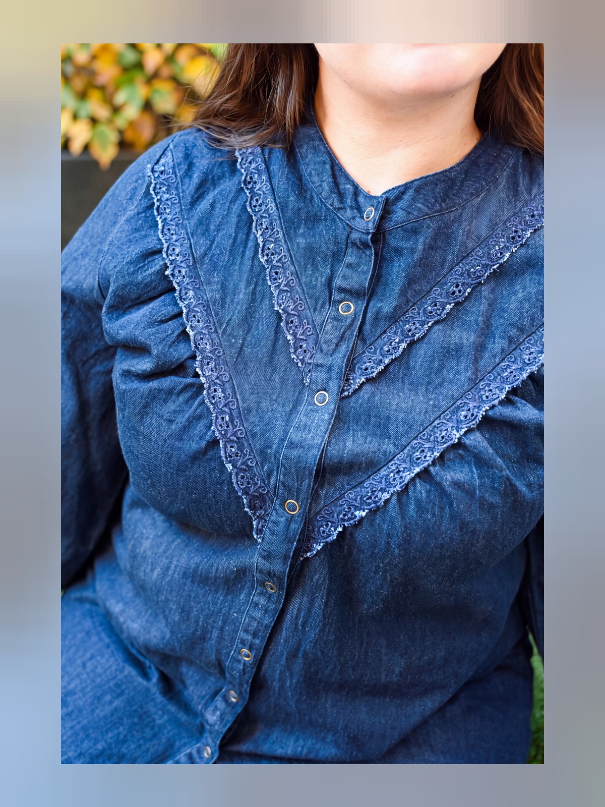 Gros plan sur le col montant, les boutons pression et la dentelle du plastron de la chemise en jean