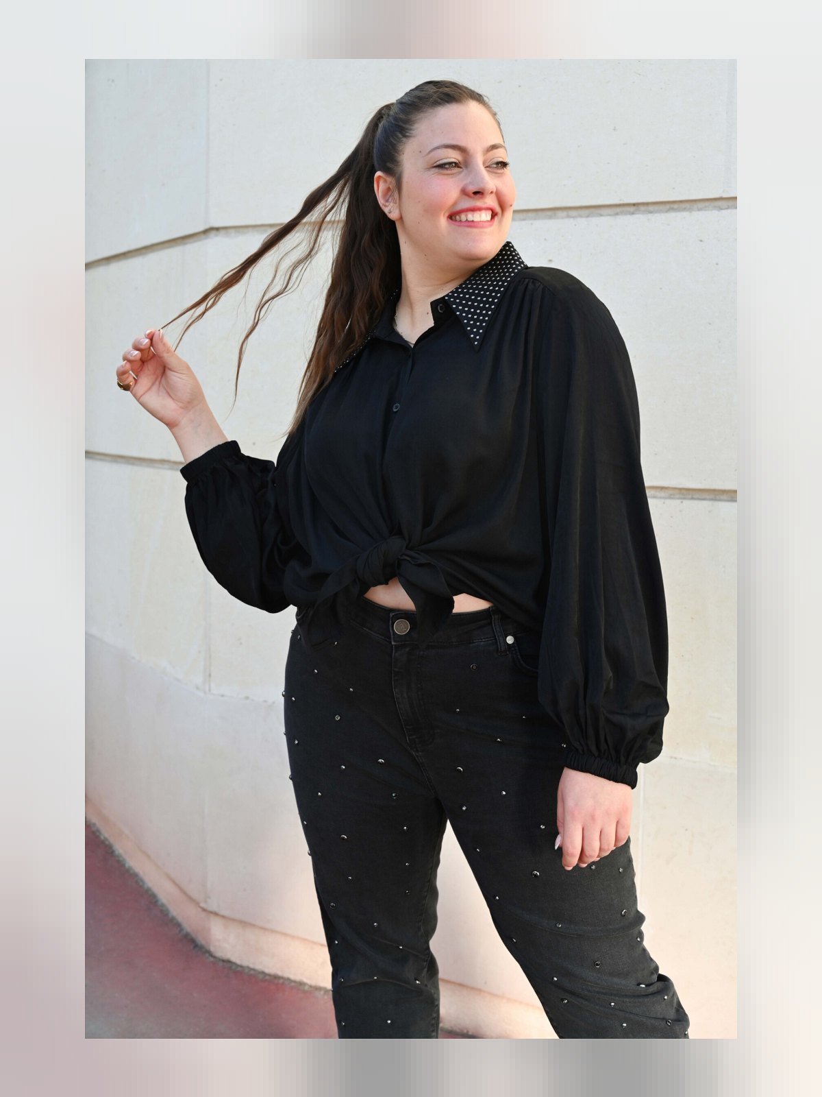 Chemise noire nouée à la taille, détail du col clouté et des manches bouffantes à poignets froncés