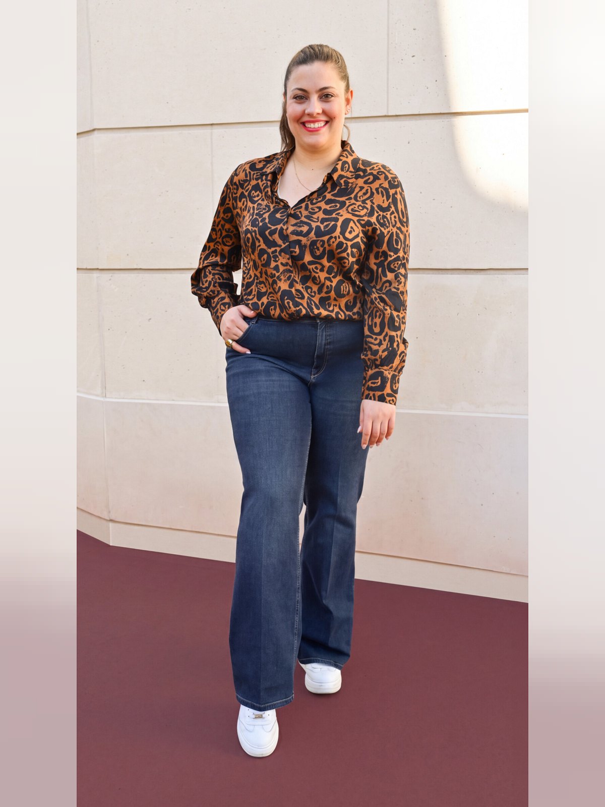 Jean flare taille haute bleu porté de face avec chemise imprimée et baskets blanches