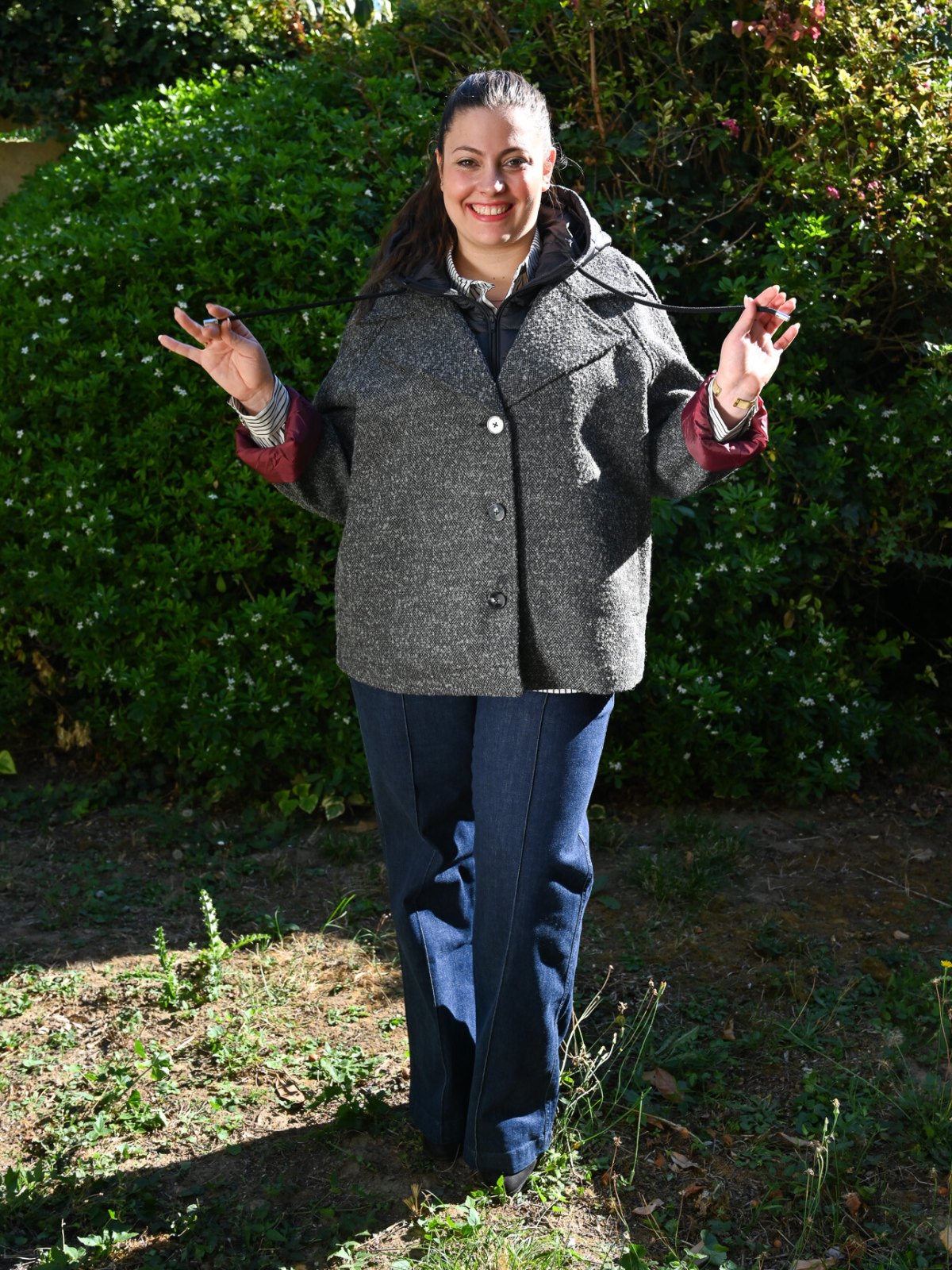 Manteau caban chiné gris en laine porté de face avec capuche amovible et boutons, sur un jean large