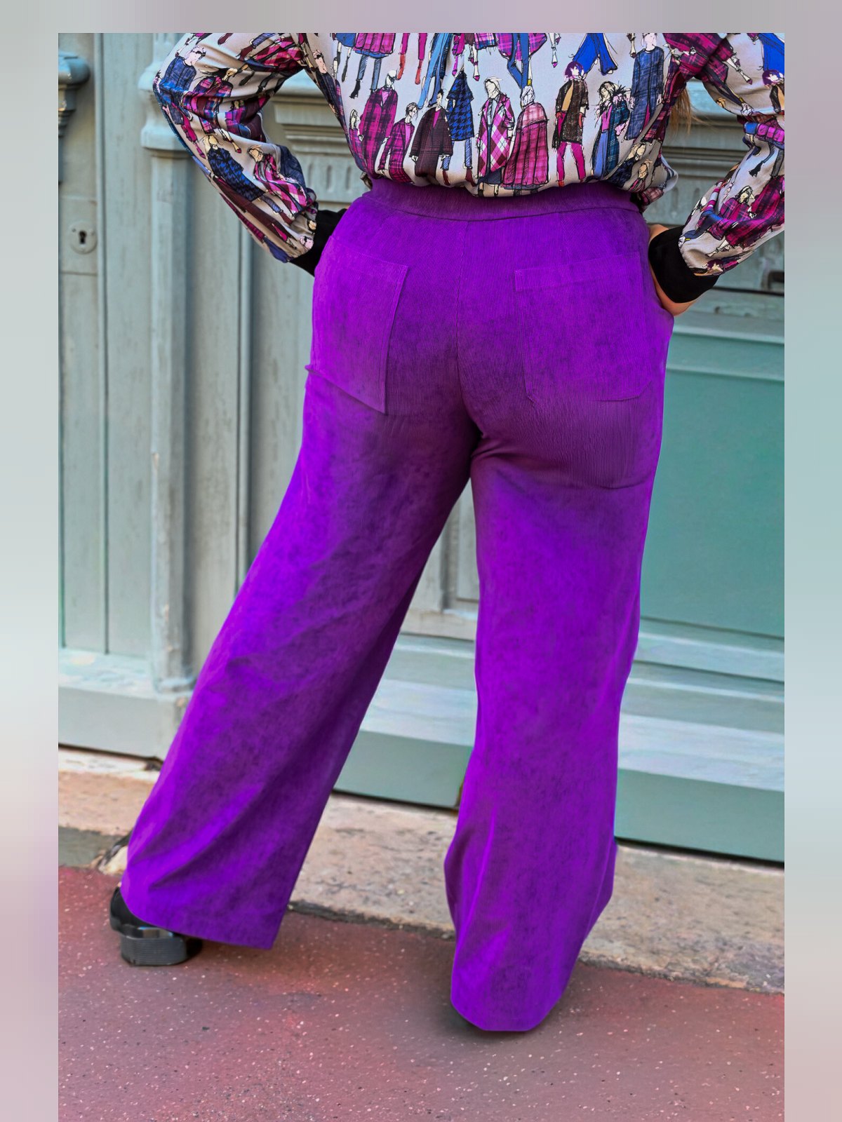 Pantalon large en velours côtelé violet vu de dos avec poches plaquées, porté avec une blouse imprimée