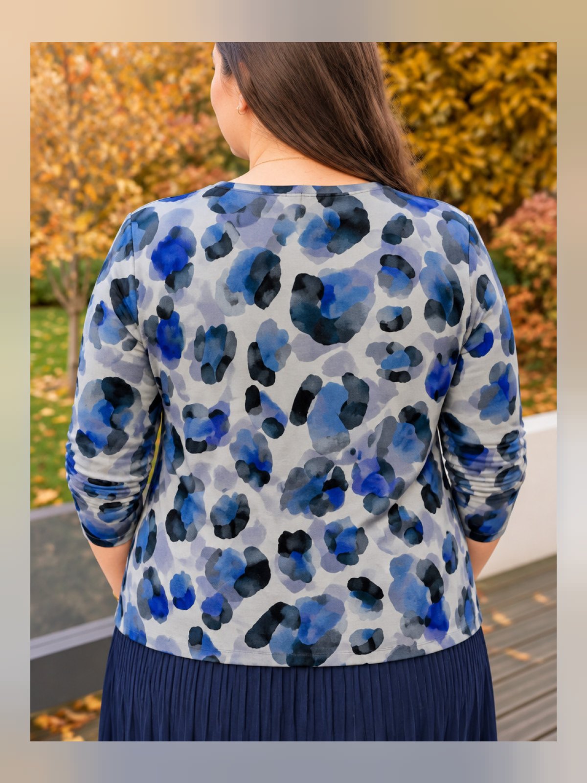 Vue de dos d'un pull à manches longues à imprimé léopard bleu, gris et noir porté avec une jupe plissée marine