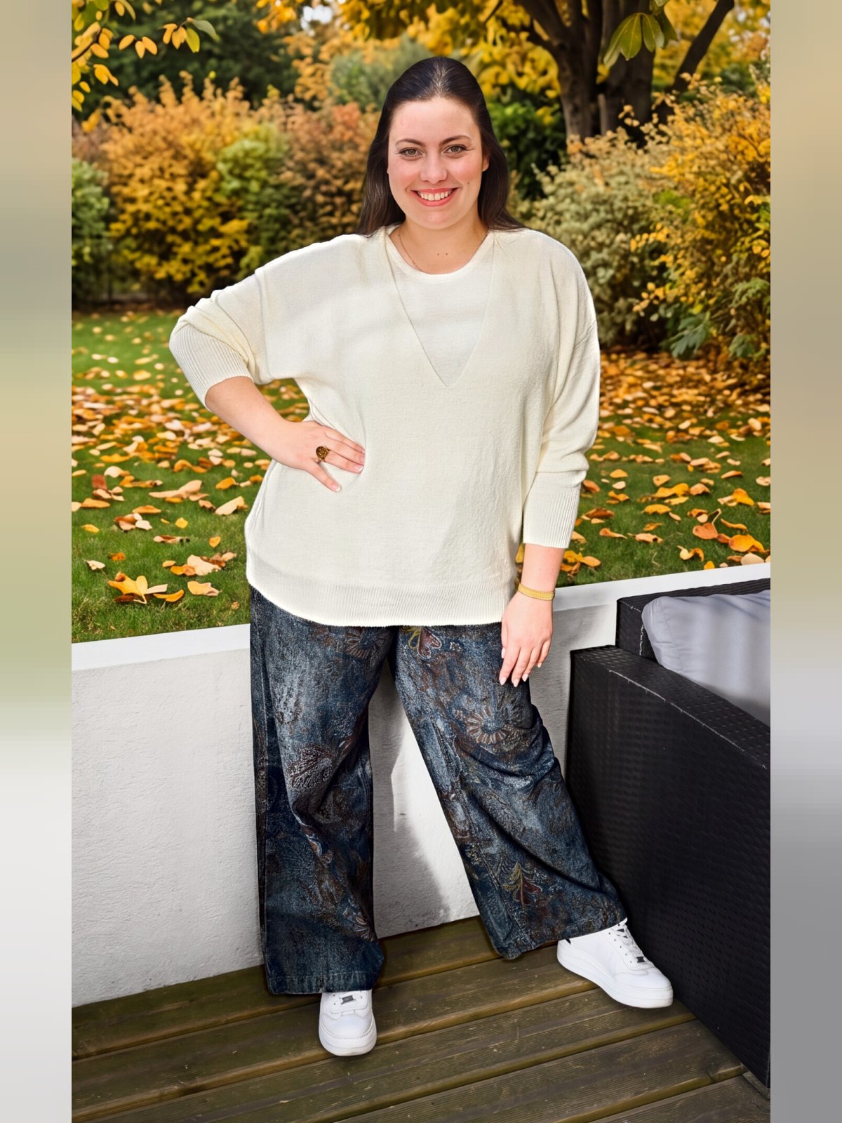 Pull écru à encolure en V superposée porté de face en pied avec un pantalon large imprimé