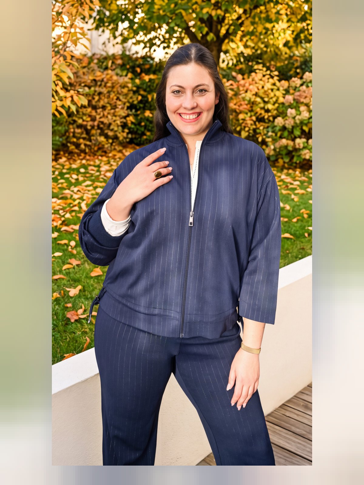 Veste marine zippée à col montant et fines rayures blanches, coulissé en bas, portée de face avec pantalon assorti