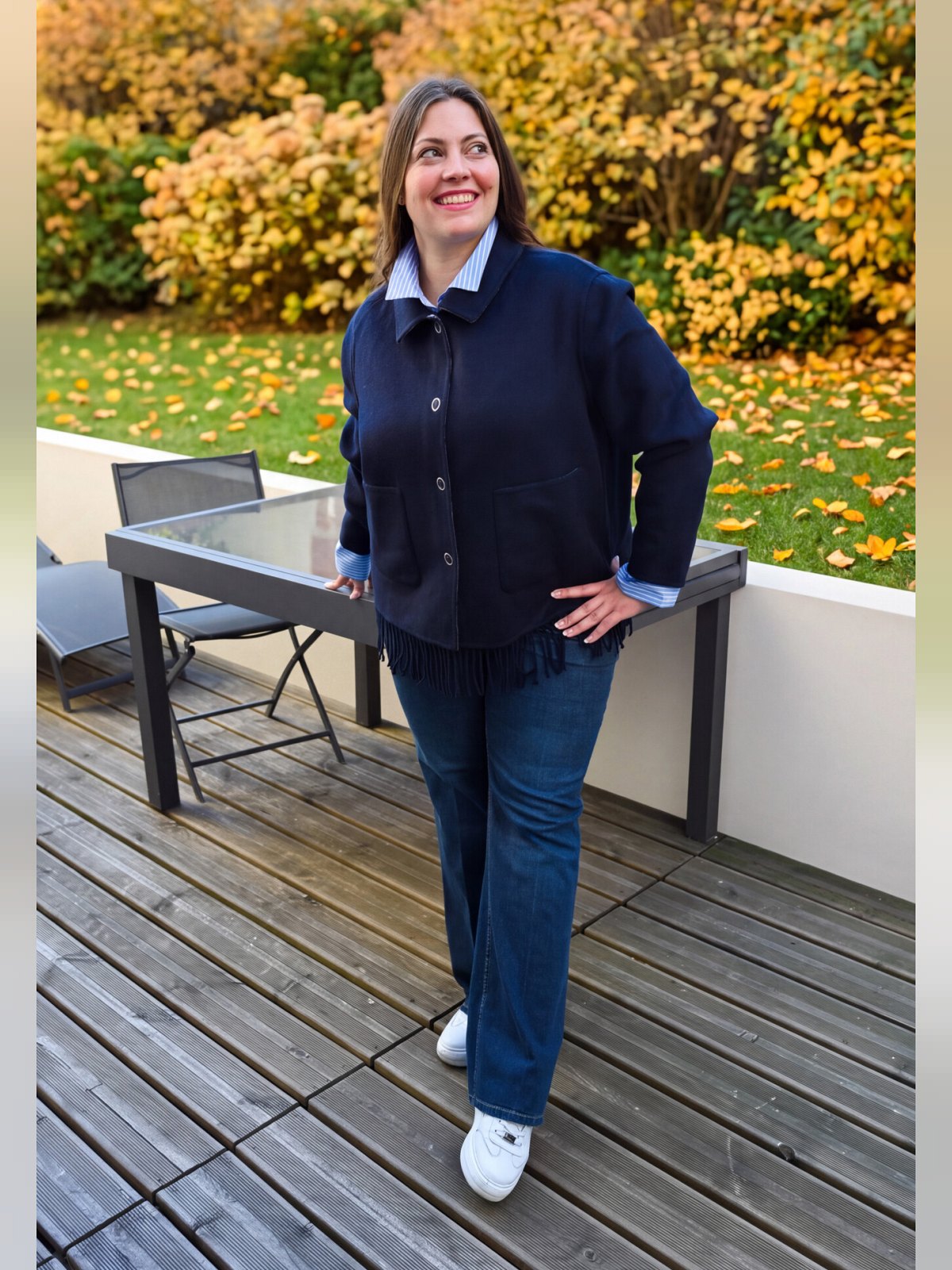 Veste réversible portée côté bleu marine uni avec boutons pression et bas frangé, sur chemise rayée et jean
